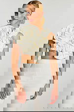 Front view of off-white crop top with oversized sculpted floral design and high-waisted pants