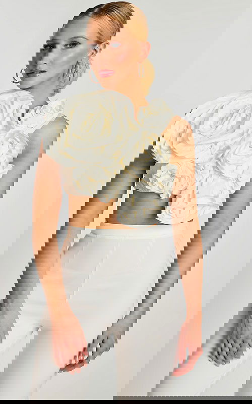 Front view of off-white crop top with oversized sculpted floral design and high-waisted pants