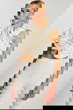 Angled view showing structured floral appliqué on one-shoulder crop top paired with sleek pants