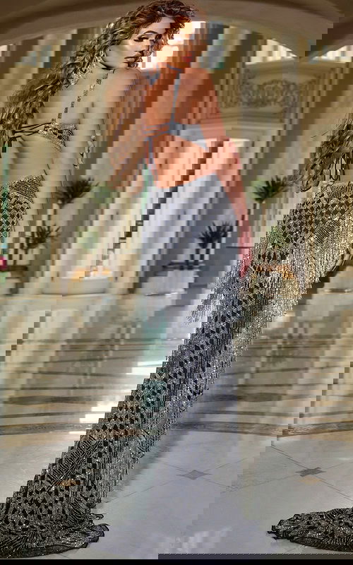 Model wearing Jovani 44723 black dress showing open back design, back view.