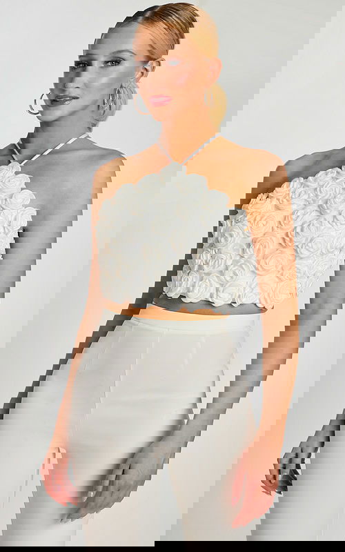 Woman wearing white 3D rosette halter crop top and high-waisted pants