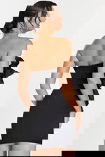 Side view of form-fitting strapless mini dress with oversized ruffle detailing