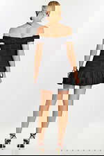 Side angle of ruched black dress with flared ruffle hem