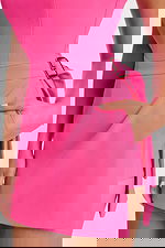 Close-up of waist and hand-in-pocket detail with gold buckle on hot pink romper dress.