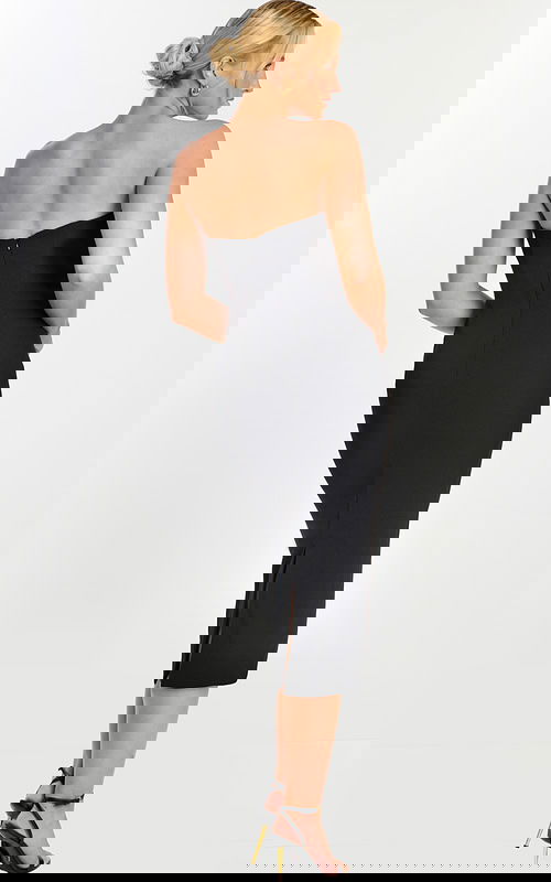 Back view of sleek black midi dress with slit and zipper closure