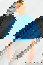 Model Wearing Cropped Denim Cape Jacket with Button Front and Wide Collar over White Pants