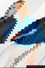 Model Unzipping Cropped Denim Cape to Show Inner Placket and Hardware Details