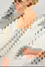 Model looking down wearing white structured jumpsuit and cape jacket