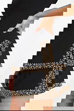 Detailed side view of gold and black beaded pocket trim on mini dress