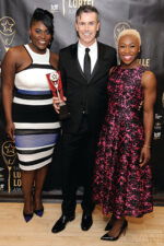 Three individuals, including one wearing the M449 multi-colored dress at the Lucille Lortel Awards.