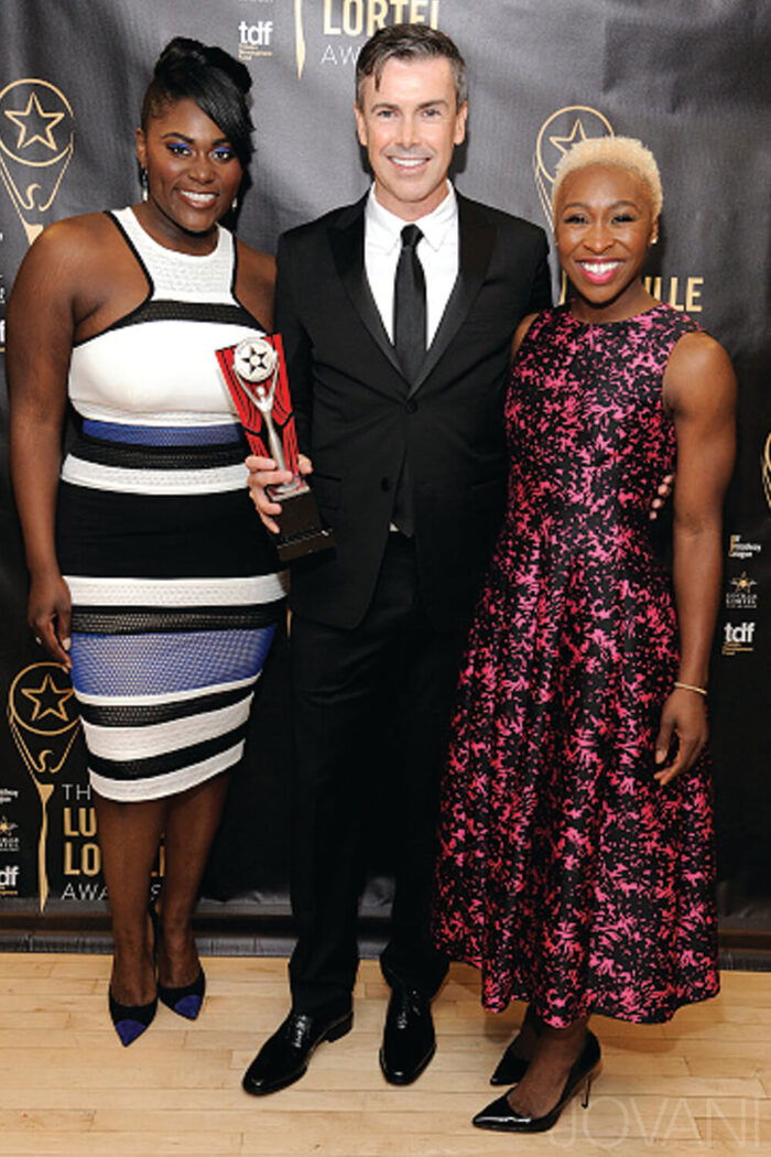 Three individuals, including one wearing the M449 multi-colored dress at the Lucille Lortel Awards.