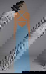 Back view of fitted evening gown with crisscross straps, open back, and softly ruched center detail