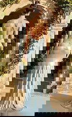 Back view of fitted embellished gown with low open back, thin straps, and softly flared hem