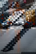 Model wearing strapless beaded mini dress with sheer floor-length overlay on city street.