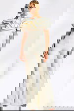 Elegant white jumpsuit with dramatic ruffled shoulders and pearl safety pin accents