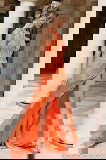 Coral orange halter neck evening gown with open back, ruched bodice detailing, and high thigh slit with flowing train.