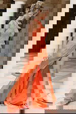 Coral orange halter neck evening gown with open back, ruched bodice detailing, and high thigh slit with flowing train.