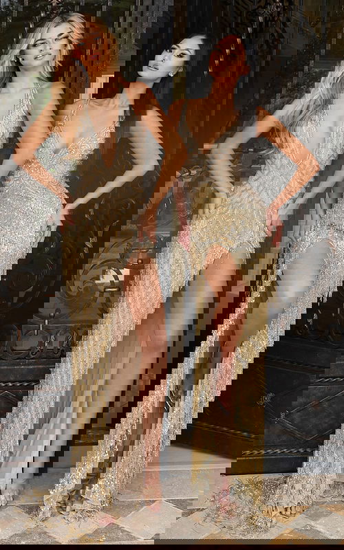 Two models wearing gold beaded fringe prom dresses with deep necklines and high slits