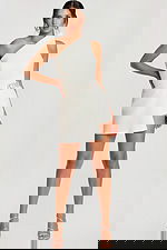 Model wearing a one-shoulder ivory romper with asymmetric hem and rhinestone heart belt