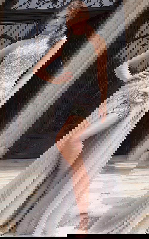 Front view of beaded halter style dress with high neckline, fitted silhouette, and sheer overskirt detail