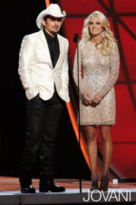 Model wearing Jovani 5278 gold short dress with long sleeves and a fitted silhouette.