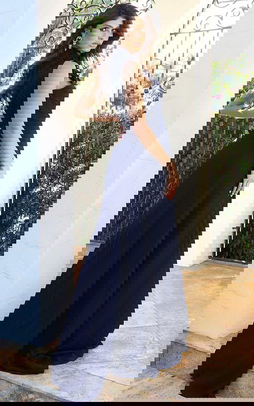 Jovani 53168 navy sleeveless high neck jumpsuit back view showing floral applique at the neckline, open back cutout, and flowing wide leg pants with sweep train