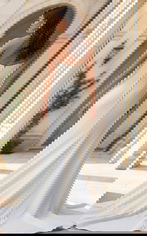 Back view of a strapless fitted gown with button back detail and flowing train.