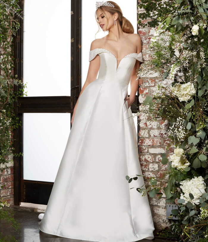 Model wearing Jovani JB07134 elegant ivory A-line gown with off-the-shoulder neckline and beaded detailing, front view.
