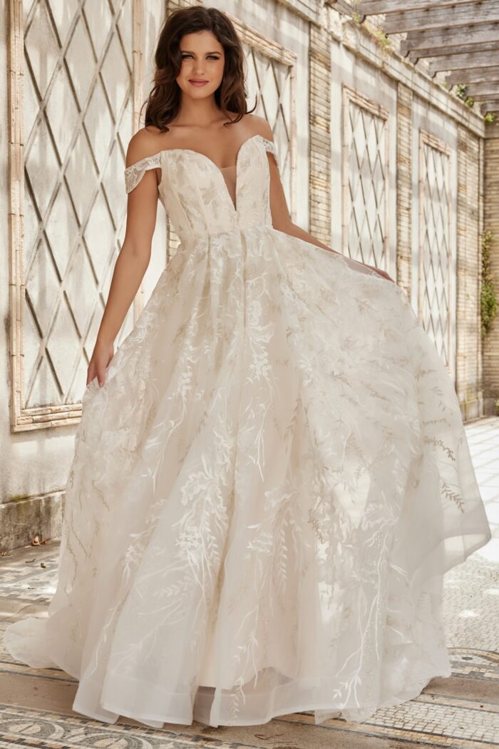 Model in front of JB220001 ivory gown with lace and off-the-shoulder sleeves.