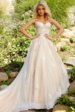 Model wearing JB24145 ivory dress with lace bodice and flowing skirt