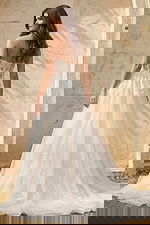 Back view of a strapless lace gown with sheer corset bodice and flowing tulle skirt.