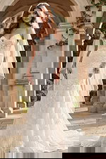 Lace wedding gown with spaghetti straps and flowing veil, featuring floral embroidery and a soft train.