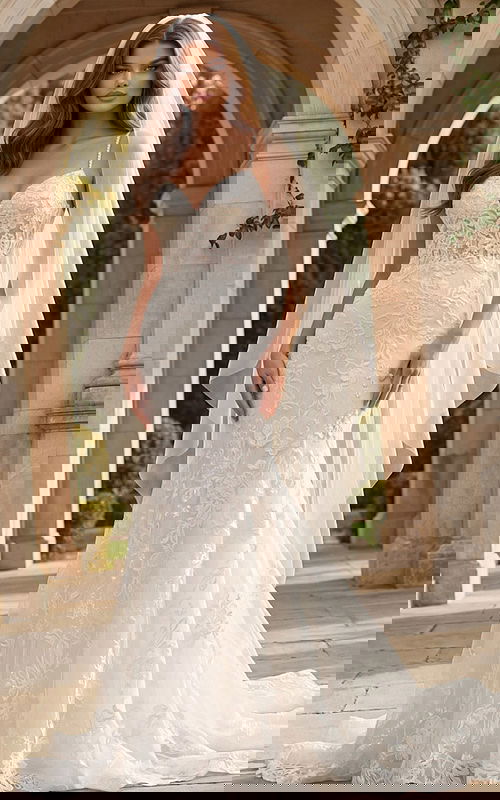 Lace wedding gown with spaghetti straps and flowing veil, featuring floral embroidery and a soft train.