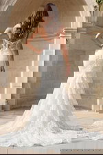 Back view of a lace mermaid gown with sheer corset back, thin straps, and embroidered train.