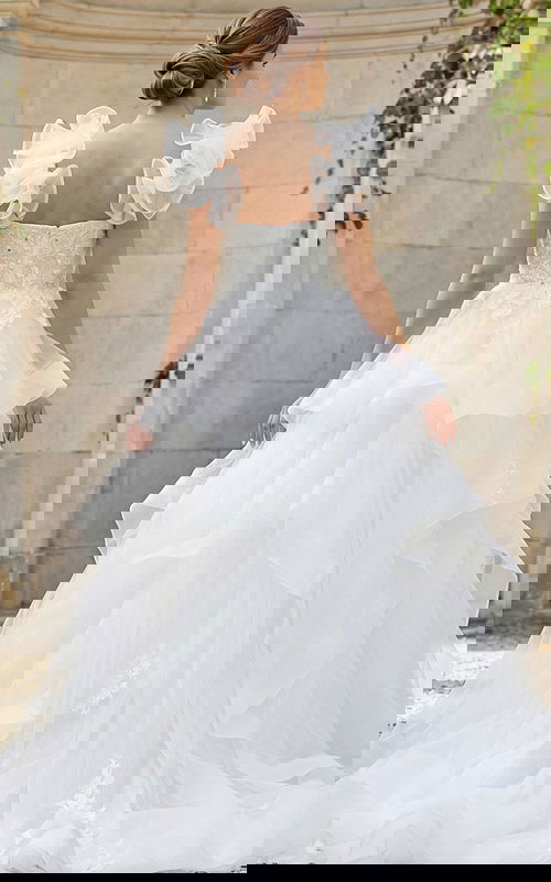 Romantic layered tulle bridal gown featuring floral bodice and soft organza ruffle sleeves