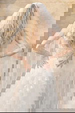 Back view of sheer floral lace wedding dress with buttons and long veil