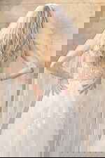 Back view of sheer floral lace wedding dress with buttons and long veil