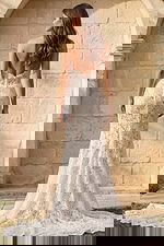 Back view of a strapless lace mermaid gown with low back, button closure, and scalloped lace train.