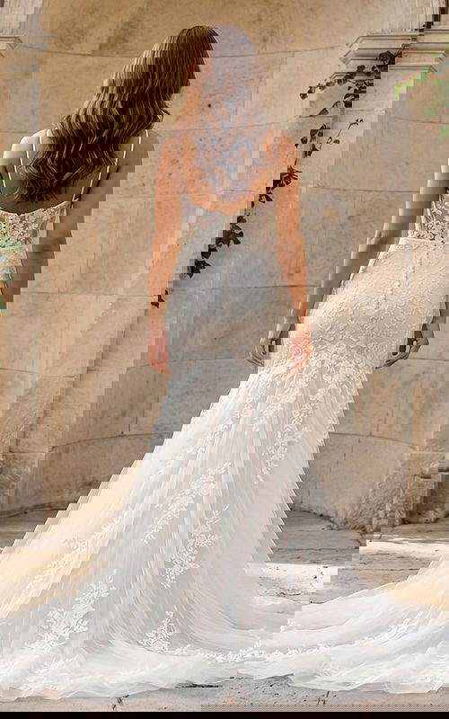 Back view of a lace mermaid gown with sheer back, thin straps, and button closure.