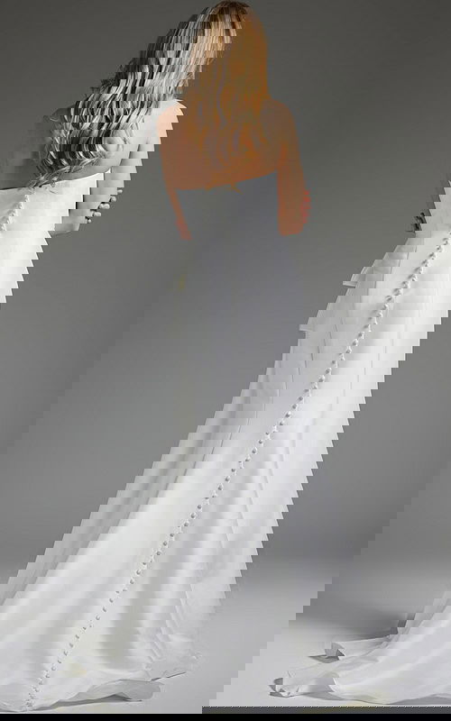 Back view of model in Jovani JB40791 white gown with button detail.