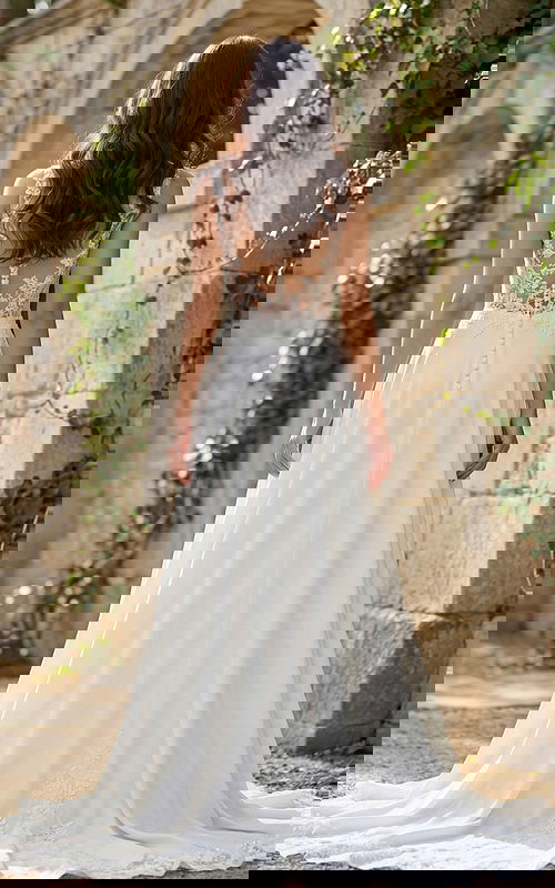 Back view of a flowing A-line bridal gown with lace illusion back, button closure, and soft chapel train