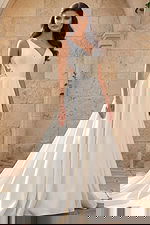 Front view of an elegant V-neck bridal gown with smooth skirt and lace side panels in an outdoor stone courtyard.