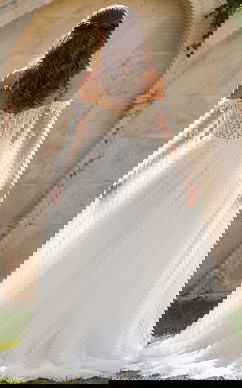 Romantic lace bridal gown with draped tulle sleeves and flowing skirt