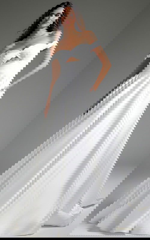 Model wearing Jovani JB42626 off-the-shoulder white dress with cutout at the bodice.