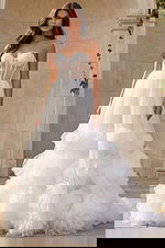 Strapless tulle ball gown with sheer corset back and oversized rosette details on the skirt.