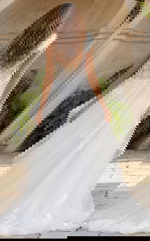 Back view of an A-line bridal gown with layered tulle skirt, illusion lace bodice, and 3D floral shoulder detail.