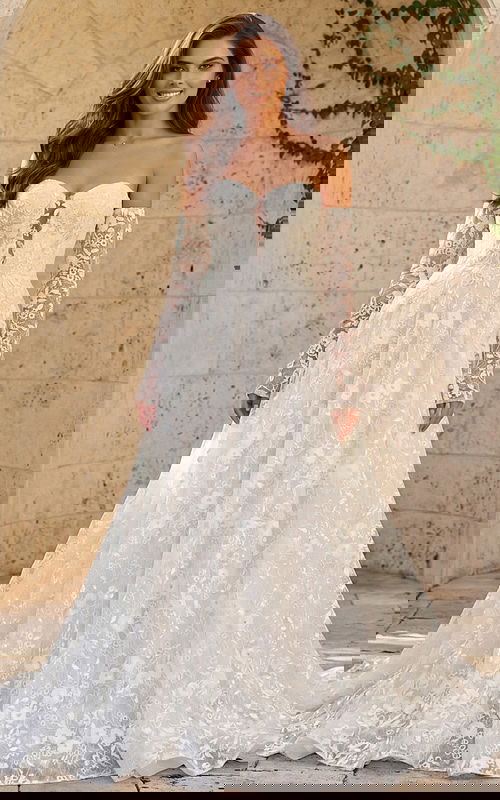 Lace off shoulder bridal gown with floral lace bodice, long sheer sleeves, and full A line skirt.