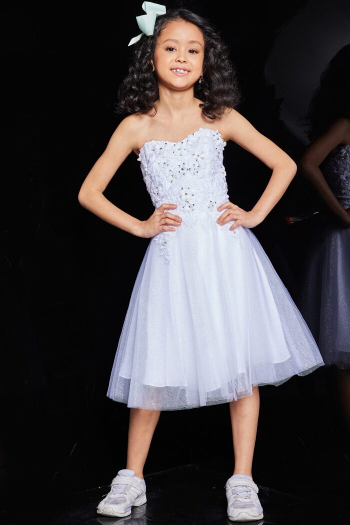 Child model wearing Jovani K07817 dress in white with floral lace bodice and tulle skirt, front view.