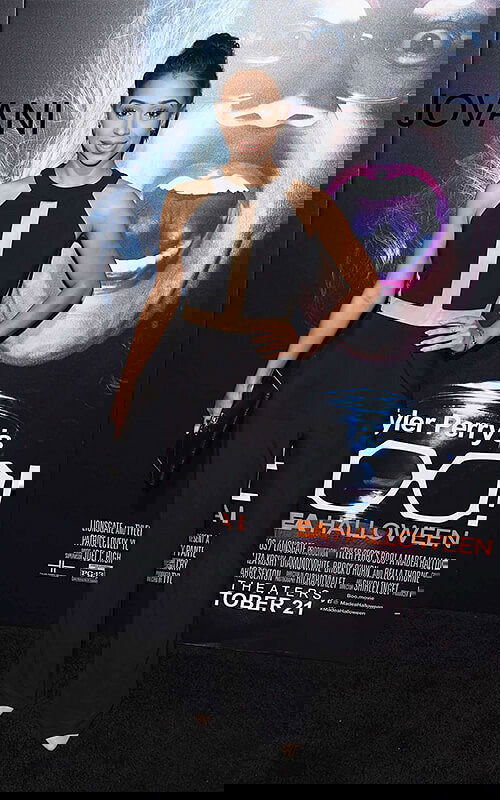 Model wearing Jovani 37953 black jumpsuit with high neckline and wide-leg pants.