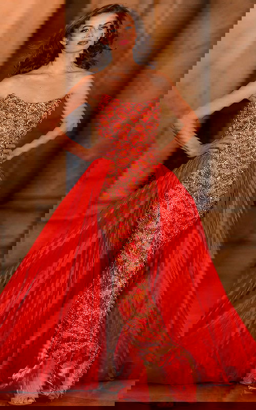 Model displaying the S04603 orange gown with elegant beadwork and a dramatic overlay.